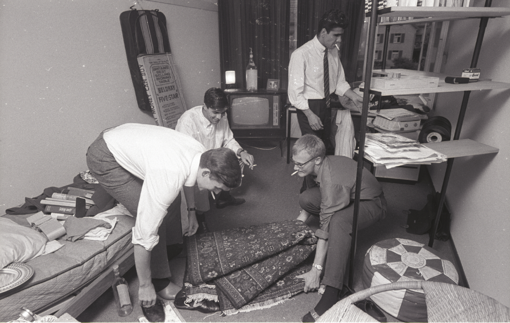Black and white picture of smoking students furnishing a room