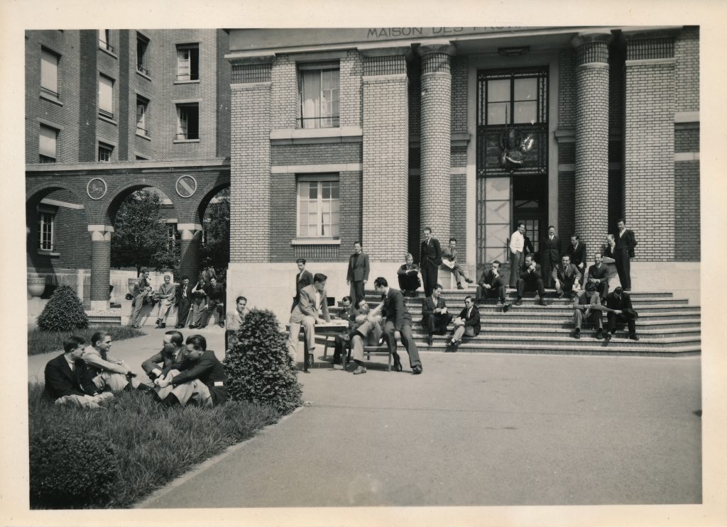 Black and white picture of students sitting and talking in front of the Maison des Provinces de France.